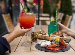 une personne tenant un verre devant une assiette de nourriture dans l'établissement CAMPANILE PARIS - Clichy Centre, à Clichy