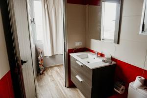 uma casa de banho com um lavatório e uma parede vermelha e branca em Casa Lara, Las Maretas em Arico