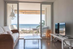 a living room with a couch and a table and a tv at LETS HOLIDAYS Beach front apartment in Gavà Mar, Pine Beach in Gavà