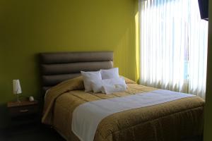 ein Schlafzimmer mit einem Bett mit zwei Kissen und einem Fenster in der Unterkunft Hotel San Felipe Suites in Arequipa