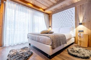 um quarto com uma cama e uma grande janela em Chalet Imbosc'chè em Livigno