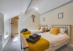 two beds in a bedroom with yellow cushions at Ty Isa in Llanfair Talhaiarn