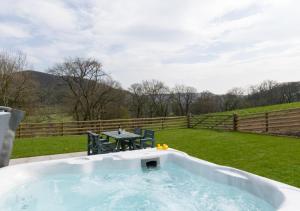 a jacuzzi tub in a yard with a table at Ty Isa in Llanfair Talhaiarn