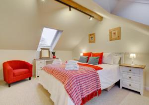 Schlafzimmer im Dachgeschoss mit einem Bett und einem roten Stuhl in der Unterkunft Ty’n Fron in Penegoes