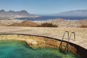 a hot tub next to a wooden deck with a view of the ocean at Casa Azul in Mindelo