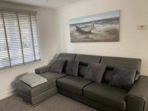 una sala de estar con un sofá verde y una pintura en Whitehouse Holiday Lettings - Luxury Serviced Properties in St Neots, Little Paxton and Great Paxton, en Saint Neots
