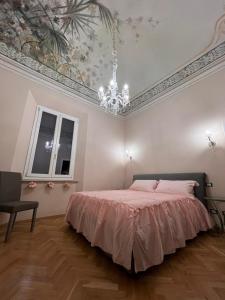 - une chambre avec un lit et un plafond orné d'un lustre dans l'établissement Affreschi sul mare, à Marina di Pisa