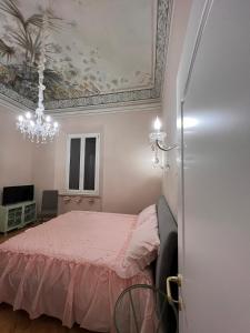 1 dormitorio con cama rosa y lámpara de araña en Affreschi sul mare en Marina di Pisa