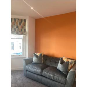 a living room with a brown couch and a window at Printer's Apartment in Pontefract