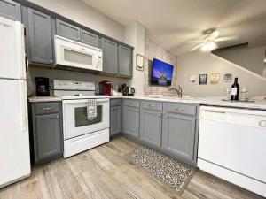 a kitchen with gray cabinets and white appliances at 3BR Townhouse Next to Disney in Orlando
