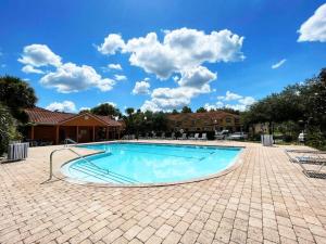 a large swimming pool with a blue sky with clouds at 3BR Townhouse Next to Disney in Orlando
