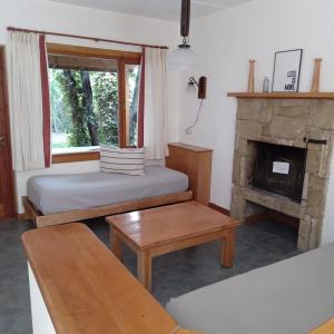 a living room with two beds and a fireplace at Refugio del Arroyo in San Martín de los Andes