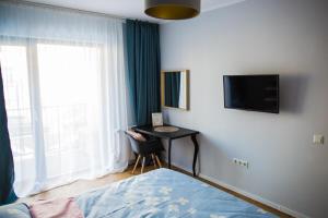 a bedroom with a bed and a desk and a television at YamaLux Apartments - HappyApartment - close to IuliusMall in Cluj-Napoca