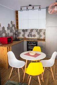 a kitchen with a table and four yellow chairs at YamaLux Apartments - HappyApartment - close to IuliusMall in Cluj-Napoca