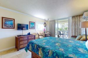 um quarto com uma cama, uma televisão e uma mesa em Islander on the Beach 333 em Kapaa