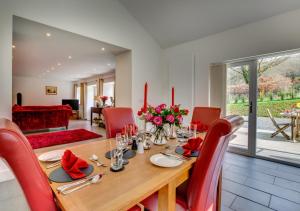 a dining room with a table and red chairs at Wisteria Cottage - Bwthyn yr Ardd in Ystrad Meurig