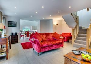 a living room with a red couch and a staircase at Wisteria Cottage - Bwthyn yr Ardd in Ystrad Meurig