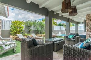 a patio with wicker chairs and a glass table at Casa Karlina in Palm-Eagle Beach