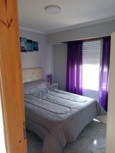 1 dormitorio con 1 cama con cortinas moradas y ventana en San Jorge en Tres Arroyos
