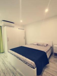 een witte slaapkamer met een bed met een blauwe deken bij Lovely two bedrooms apartment. in Flic-en-Flac
