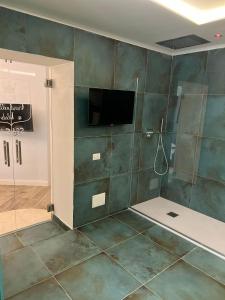 a bathroom with a shower and a television on the wall at Real Giardinetto a Toledo in Naples