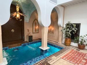 a swimming pool in a house with an archway at Riad Al Ibtikar in Marrakech