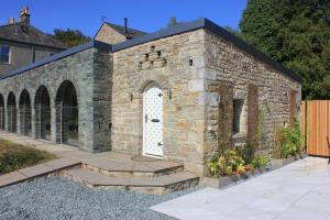 un antiguo edificio de ladrillo con una puerta blanca en The Old Poolhouse, en High Bentham