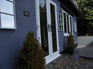 una casa azul con una puerta blanca y algunos árboles en The Mill at Glynhir, en Ammanford