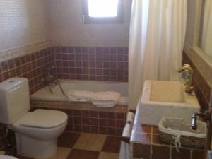 a bathroom with a toilet and a tub and a sink at Complejo Rural El Marañal in Caspueñas