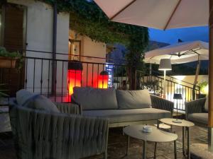 a patio with a couch and tables and an umbrella at Hotel Iride by Marino Tourist in San Vito lo Capo