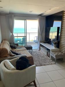 a living room with a couch and a television and a balcony at Terraço do Atlântico in Fortaleza