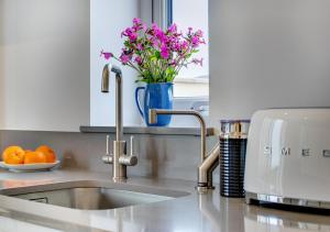 um balcão de cozinha com um lavatório e um vaso de flores em Morannedd em Aberdaron