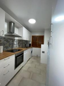 a kitchen with white cabinets and a sink and a refrigerator at Puerta del Hierro in Sigüenza +20 photos