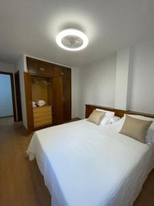 a bedroom with a large white bed with a light at Puerta del Hierro in Sigüenza