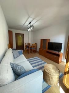 a living room with a white couch and a television at Puerta del Hierro in Sigüenza