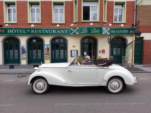 Ein Mann fährt ein weißes Auto die Straße runter. in der Unterkunft Hotel De La Paix in Albert