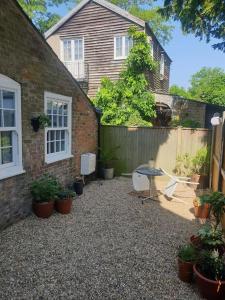 Walmer, Deal stunning coach house apartment في Walmer: فناء به طاولة وكراسي أمام المنزل