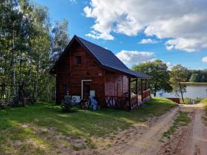 a small wooden cabin on the side of a lake at Domek Letniskowy, Dom Całoroczny Eryś 80m2. Przy Plaży. Wynajem. Odpoczynek in Książki