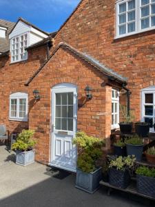 uma casa de tijolos com uma porta branca e vasos de plantas em The Peel Aldergate em Tamworth