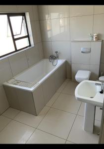 a bathroom with a tub and a toilet and a sink at Almina villa in Windhoek