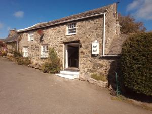 an old stone house with a door in a street at Pandy cymunod in Bryngwran