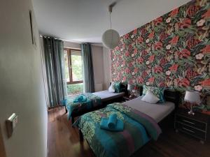 1 dormitorio con 2 camas y pared con papel pintado con motivos florales en SAS Apartamenty Baron, en Szczecin