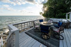 una terraza con mesa, sillas y agua en Cozy Lakefront Cottage, en Huron