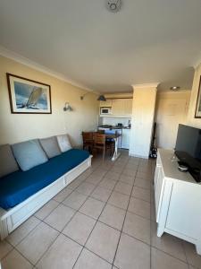 uma sala de estar com um sofá azul e uma cozinha em Superbe T2 à Lacanau 50m l’océan em Lacanau
