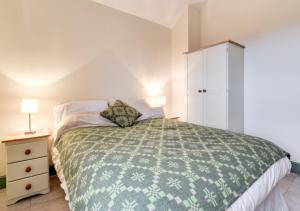 LlanonにあるTy Jimのベッドルーム1室(緑の毛布と白いキャビネット付きのベッド1台付)