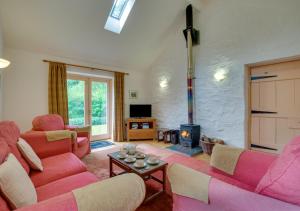 a living room with pink furniture and a fireplace at Stabal Pant y Lludw in Machynlleth