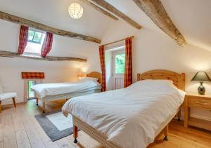 a bedroom with two beds and two windows at Stabal Pant y Lludw in Machynlleth
