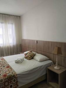 ein Schlafzimmer mit einem Bett und einem Tisch mit einer Lampe in der Unterkunft Flat Imóvel na Praia de Camburi , Vista lateral pro Mar in Vitória