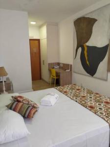 ein Schlafzimmer mit einem großen weißen Bett mit einem Gemälde an der Wand in der Unterkunft Flat Imóvel na Praia de Camburi , Vista lateral pro Mar in Vitória