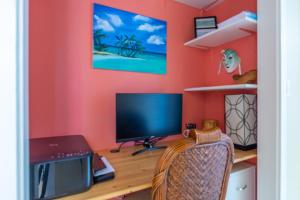 Habitación con escritorio con monitor y ordenador portátil. en Kailua Village Resort 605, en Kailua-Kona